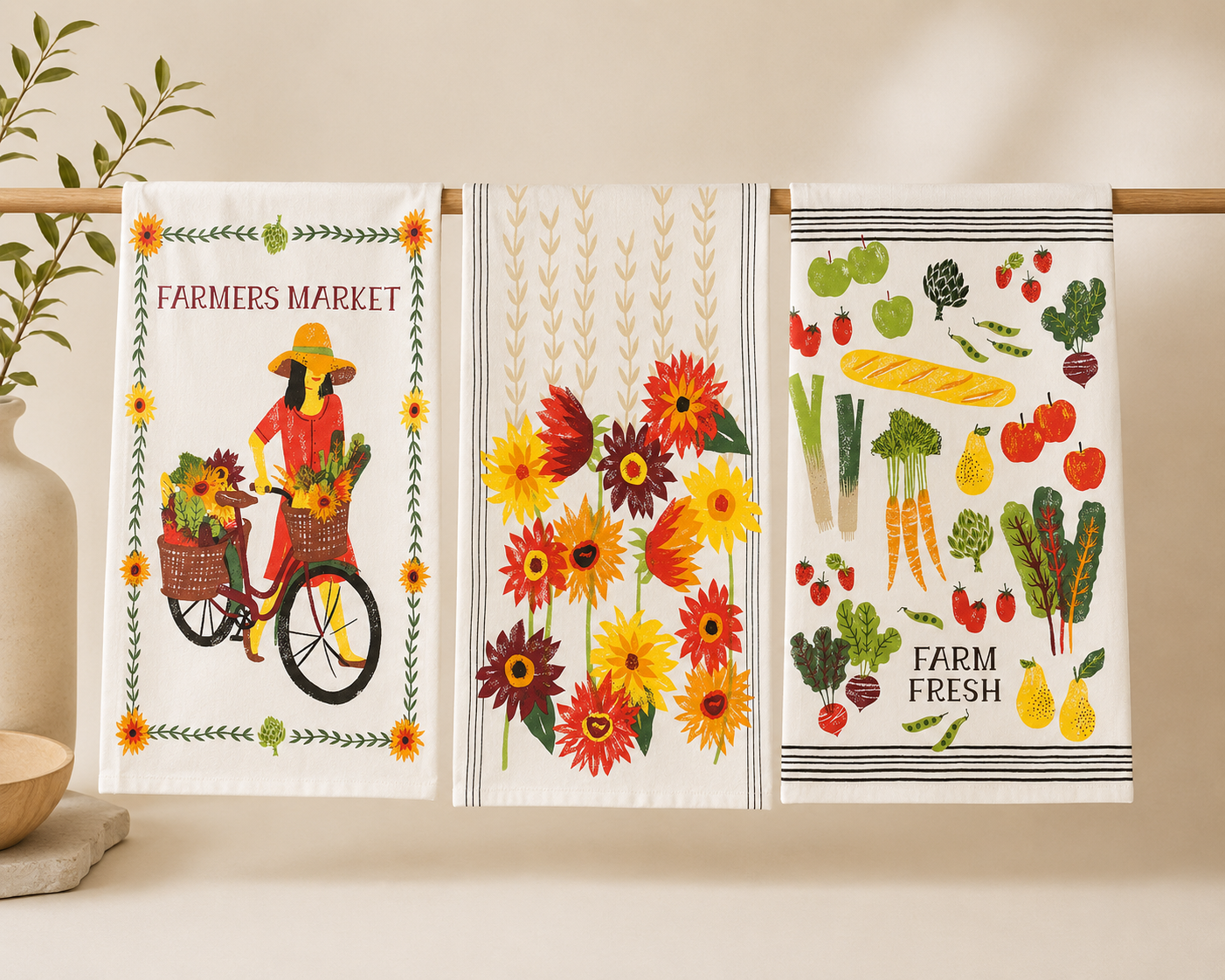 Three decorative kitchen towels with farm-themed designs on a wooden rack.