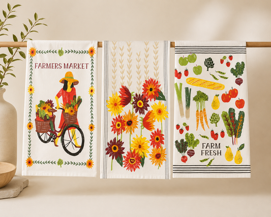 Three decorative kitchen towels with farm-themed designs on a wooden rack.